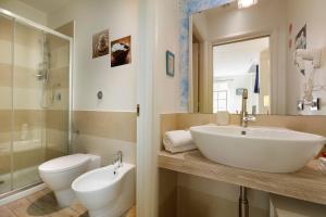 a bathroom with a sink and a toilet and a mirror at Hotel La Villa Del Mare in Cagliari