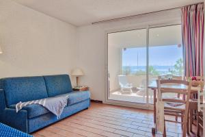 a living room with a blue couch and a table and a balcony at Résidence Pierre & Vacances Louis Lumière in Bandol