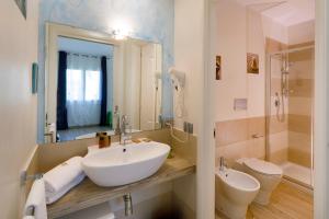 a bathroom with a sink and a toilet and a mirror at Hotel La Villa Del Mare in Cagliari