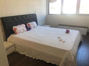 una camera da letto con letto, lenzuola e cuscini bianchi di Apartment Qiu lux costa da caparica a Costa da Caparica