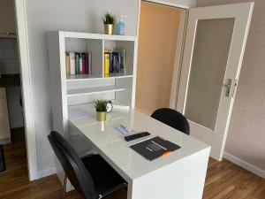 - un bureau blanc avec deux chaises et une étagère à livres dans l'établissement 1,5 Z Apartment mit Balkon direkt am Hauptbahnhof, à Neumünster