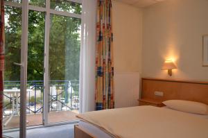 a bedroom with a bed and a large window at Kurparkhotel Das Kleinod in Bad Kissingen