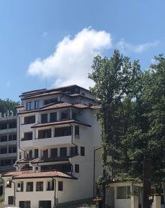 a white building with a tree in front of it at Apartment FREEDOM in Shkorpilovtsi