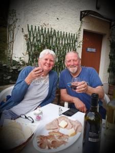 a man and woman sitting at a table with a glass of wine at B&B Naquane 2 in Capo di Ponte