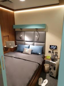 1 dormitorio con cama con almohadas azules y ordenador portátil en sleep 'n fly Sleep Lounge, SOUTH Node - TRANSIT ONLY en Doha