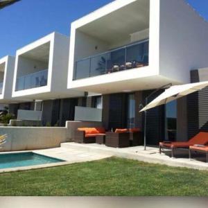 uma grande casa branca com piscina e guarda-sol em Luxus Chalet Casas Blancas em Cala Mendia