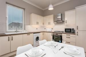 a kitchen with white cabinets and a white table and chairs at Seaforth Suite - Donnini Apartments in Ayr +12 photos