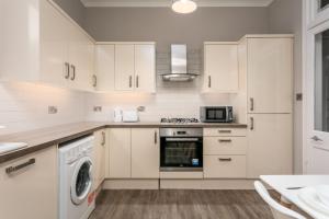 a kitchen with white cabinets and a washer and dryer at Seaforth Suite - Donnini Apartments in Ayr