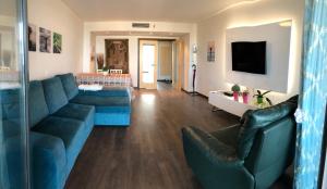 un soggiorno con divano blu e TV di Apartment Qiu lux costa da caparica a Costa da Caparica