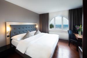 a bedroom with a large bed and a desk and a window at Hotel Uto Kulm - autofrei in Zurich