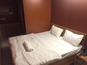 a bed with white sheets and a towel on it at Dream Vision Guest House in Diu