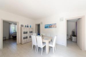 a white dining room with a table and white chairs at CASA ROSA- Appartamento nel verde con posto auto, zona tranquilla,wifi gratuito,aria condizionata in Rapallo