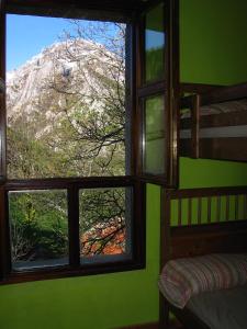 um quarto com 2 janelas com vista para a montanha em Albergue Peña Castil em Sotres