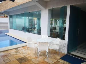un tavolo e sedie su un patio con piscina di Praia Carneiros Flat Hotel a Tamandaré