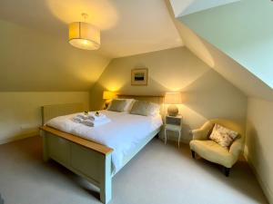 a bedroom with a large bed and a chair at Dunvegan Castle Gardens Cottage in Dunvegan