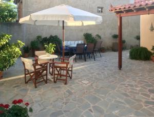 a patio with a table and chairs and an umbrella at Maria Pantermou Rooms in Skala Eresou