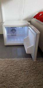 an open refrigerator sitting on the floor next to a couch at Privatzimmer Essy in RE in Recklinghausen