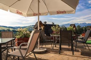 un patio con mesas, sillas y una sombrilla en Biały Dunajec Resort & Spa, en Biały Dunajec