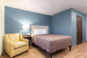 a bedroom with a bed and a yellow chair at WoodSpring Suites Indianapolis Airport South in Indianapolis