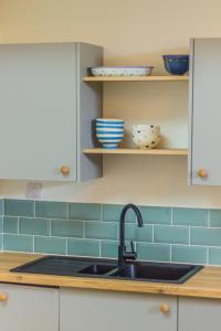 a kitchen with a sink and blue tiles at The Old Sunday School in Helston