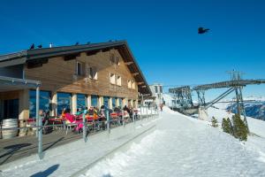 un grupo de personas sentadas en mesas fuera de un lodge de esquí en Berghaus Niederhorn, en Beatenberg