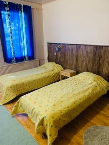two beds with yellow covers in a room at Majatalo Tyrni in Nakkila