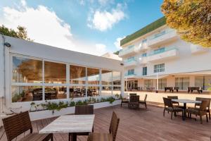 an exterior view of a building with tables and chairs at Hotel El Pinar in Cala Llonga