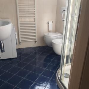 La salle de bains est pourvue de carrelage bleu, de toilettes et d'un lavabo. dans l'établissement Serafina's House, à Borgio Verezzi