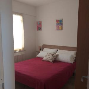 - une chambre avec un lit rouge et 2 oreillers dans l'établissement Serafina's House, à Borgio Verezzi