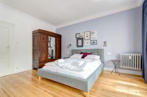 biała sypialnia z łóżkiem i drewnianą podłogą w obiekcie Dom & House Apartments Old Town Dluga w Gdańsku