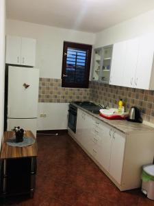 uma cozinha com armários brancos e um frigorífico branco em Apartman Vukoja Pakostane em Pakoštane
