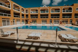 a large building with a swimming pool in front of a building at El Chulo Apartamento in El Cotillo