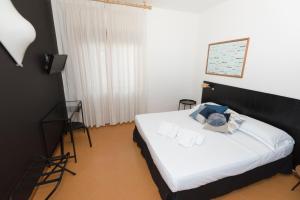 a bedroom with a bed with white sheets and a television at Mami Sabaudia Hotel in Sabaudia