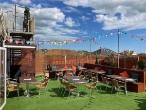 a patio with tables and chairs on the grass at The Greenwich Rooms - Burger & Bird Bar & Restaurant in Peacehaven