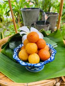 a bowl of oranges on a plate on a table at Baan Sithepaban Guesthouse in Phitsanulok