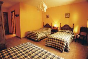 Duas camas num quarto com paredes amarelas em La Trocha De Hoyorredondo em Hoyorredondo