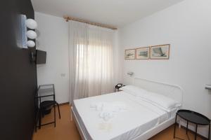 a bedroom with a white bed and two chairs at Mami Sabaudia Hotel in Sabaudia