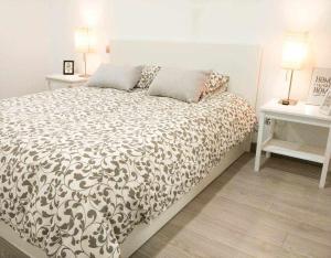 ein Bett in einem Schlafzimmer mit zwei Tischen und zwei Lampen in der Unterkunft LA CASITA DEL JARDiN in Villaverde de Arriba