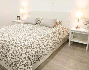 a bed in a bedroom with two tables and two lamps at LA CASITA DEL JARDiN in Villaverde de Arriba