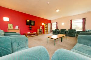 a waiting room with blue chairs and a red wall at YHA Sheringham in Sheringham