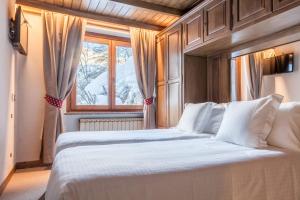 Schlafzimmer mit einem großen weißen Bett und einem Fenster in der Unterkunft Hotel Breithorn in Breuil-Cervinia