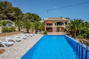 een zwembad met stoelen en een huis bij Diana - pretty holiday property with garden and private pool in Benissa in Benissa