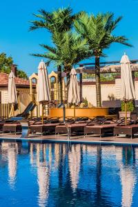 a swimming pool with chairs and umbrellas and palm trees at Hayat Spa Hotel in Pyatigorsk