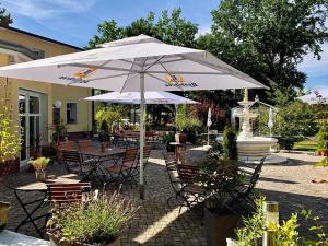 a patio with tables and chairs with an umbrella at Pension Am Waldguertel in Forst