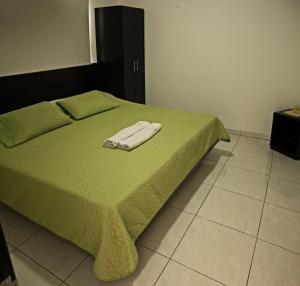 un letto con una coperta verde e un asciugamano sopra di Hotel Centro Real a San Gil