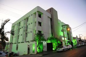 a green building with cars parked in front of it at Ouro Cerrado Palace Hotel in Patrocínio