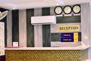 een receptiebalie met klokken aan de muur bij HOTEL UMA PALACE in Gorakhpur