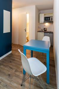 a kitchen with a table, chairs, and a refrigerator at Ténéo Apparthotel Bordeaux Gare Saint Jean in Bordeaux