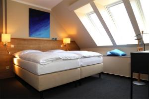 a bedroom with a large bed with two windows at Hotel Altstadt-Passage in Wittingen