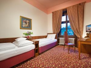 um quarto com 2 camas, uma secretária e uma cadeira em EA Zamecky Hotel Hruba Skala em Hrubá Skála